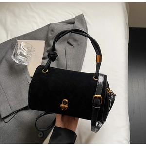 Detail of black suede and smooth leather stitching bag with gold twist-lock closure