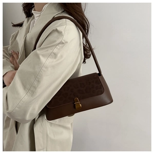 Detailed view of brown underarm bag with leopard print flap and gold clasp on trench coat