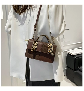 Detail of a brown leather shoulder bag with leopard print panels and decorative scarf