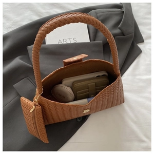Detail of brown woven underarm bag showing interior capacity with phone and cosmetics