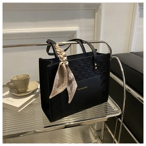 Detail of black tote bag with embossed checkered texture and decorative silk scarf wrap