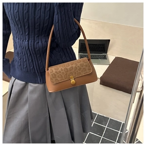 Close-up of vintage brown leather underarm bag with leopard print flap and metal lock