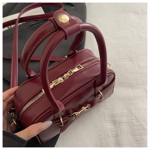 Close-up of vintage wine red handbag featuring premium gold metal zipper and handle detail