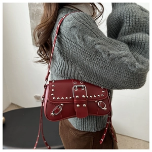 Detailed close-up of dark red shoulder bag featuring silver rivets and metal buckle design