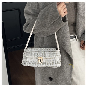 Detailed macro view of the white tweed underarm bag with gold stitching and metal clasp