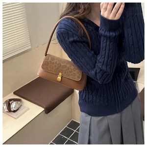 Close-up of vintage brown shoulder bag featuring leopard print texture and gold clasp