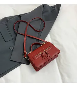 Detail der dunkelroten Vintage-Umhängetasche mit Doppelreißverschlüssen und Lederquasten