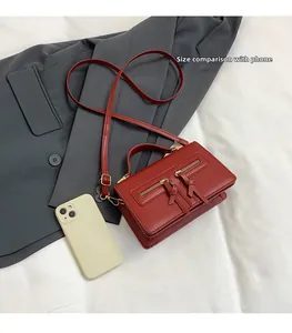 Draufsicht der roten Vintage-Umhängetasche mit Doppelreißverschluss und Smartphone