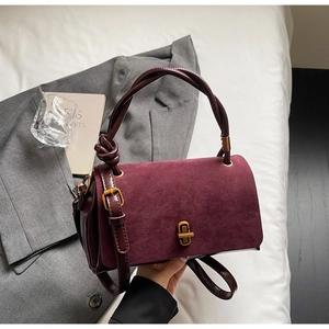 Detail of burgundy suede flap bag with vintage gold turn-lock and knot strap handle