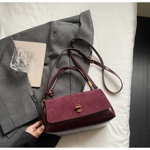 Close-up of suede and leather patchwork crossbody bag with elegant gold metal twist lock