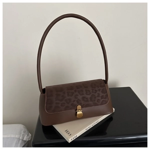 Detail of vintage baguette bag featuring leopard print flap and aged gold heart clasp