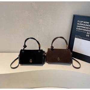 Detail of minimalist suede handbags featuring a knot handle and golden twist lock closure