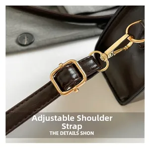 Detail view of the adjustable strap with golden buckle on dark brown leather handbag