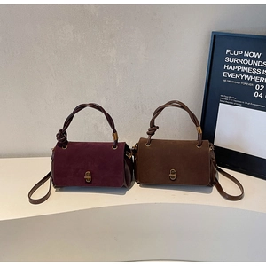 Close-up of suede crossbody bags with woven handles and elegant gold metal locks
