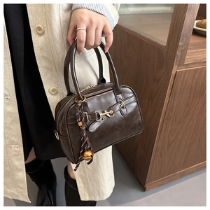 Detailed close-up of dark brown vintage Boston bag featuring gold metal hardware accents