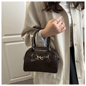 Close-up of a deep brown Boston handbag featuring a glossy finish and metal horsebit detail