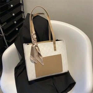 Chic white checkered tote bag with brown leather pocket and decorative silk scarf accessory