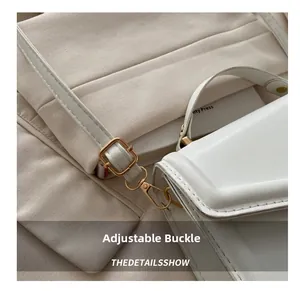 Macro shot of white matte leather bag showing golden metal buckle and lobster clasp detail