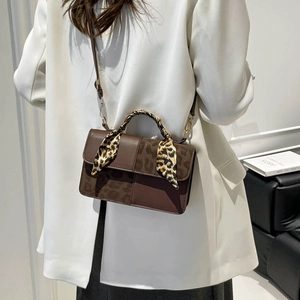 Brown leather crossbody handbag with leopard print flap and silk scarf handle detail