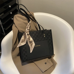 Elegant black leather tote bag with silk scarf accent on a blazer for workwear style