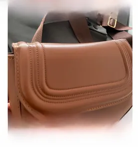 Detail of brown leather saddle bag featuring triple U-shaped stitching and gold buckles