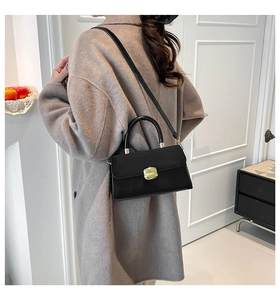 Elegant black leather square handbag shown worn crossbody in a modern home setting