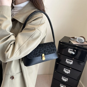 Retro black shoulder bag with leopard print flap and gold clasp on a female model
