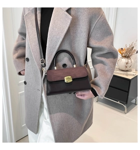 Detail of two-tone brown crossbody bag with gold buckle on a grey wool coat outfit