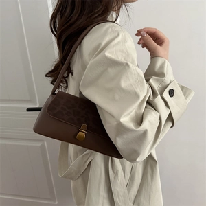 Vintage dark brown shoulder bag with leopard print flap and gold clasp on a beige coat