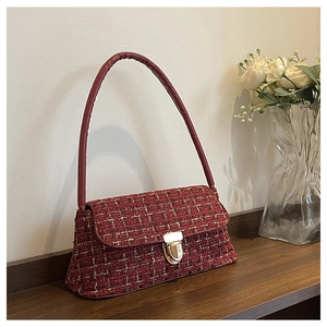 Detail of red tweed shoulder bag with gold clasp and elegant textured woven finish