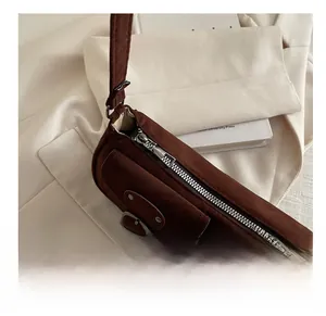 Gros plan détaillé sur la fermeture éclair en métal et la boucle d'un sac en daim marron
