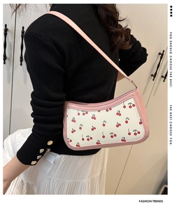 Shoulder bag with pink trim and cherry print shown on model for fashion style