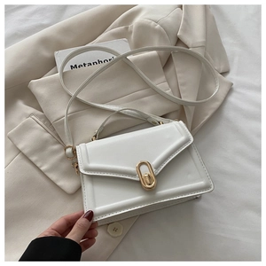 Detail of white structured handbag with golden oval metal clasp and adjustable strap