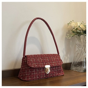 Detail of red tweed shoulder bag featuring woven texture and gold metal buckle