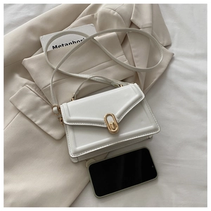 Detailed view of white leather crossbody bag with gold buckle next to a phone for size