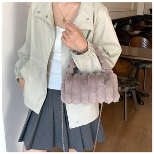 Détail d'un sac à main en fausse fourrure gris-mauve avec poignée ronde et chaîne argentée