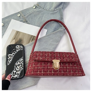 Close-up of wine red tweed shoulder bag with gold clasp on denim jacket background