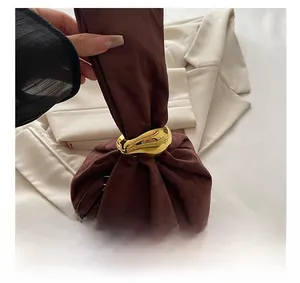 Detail of dark brown suede bucket bag with unique drawstring and gold ring accent