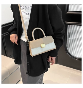 Detail of contrast leather handbag with golden metal turn-lock and adjustable strap