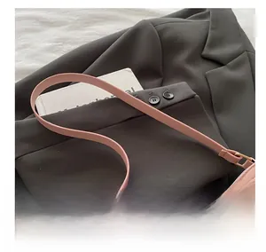 Detailed close-up of pink leather shoulder strap with gold buckle and cherry pattern print