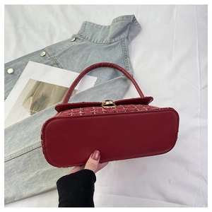 Detail of red tweed handbag featuring a gold metal twist lock and leather base