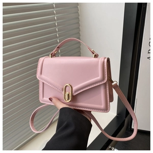 Detailed view of pink textured faux leather handbag with golden metal turn-lock buckle