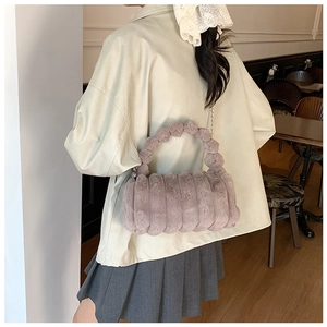 Détail du sac polochon en fausse fourrure mauve avec texture rayée et anse perlée