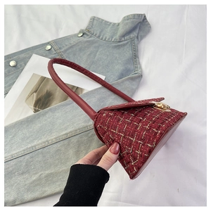 Detail of red tweed underarm bag with gold metallic threads and secure twist lock
