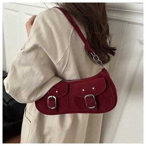 Détail du sac sous le bras en daim rouge avec boucles et bandoulière en chaîne