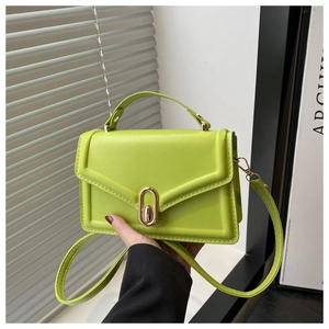 Detail of green faux leather handbag featuring a V-shaped flap and gold oval twist lock