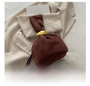 Detail showing the dark brown suede bucket bag with gold-tone hardware on white fabric