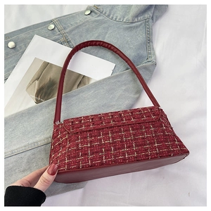 Close-up of burgundy tweed underarm bag with yellow plaid texture and leather strap