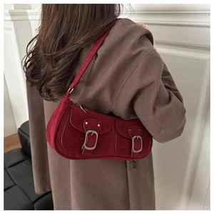 Détail du sac sous le bras en daim rouge avec doubles poches à rabat et boucles en métal