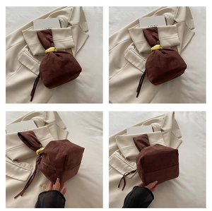 Macro details of dark brown suede bucket bag with gold pebble hardware and side zipper